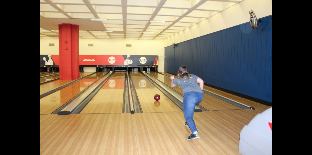 Hispanic female releasing her bowling ball down the bowling lane.