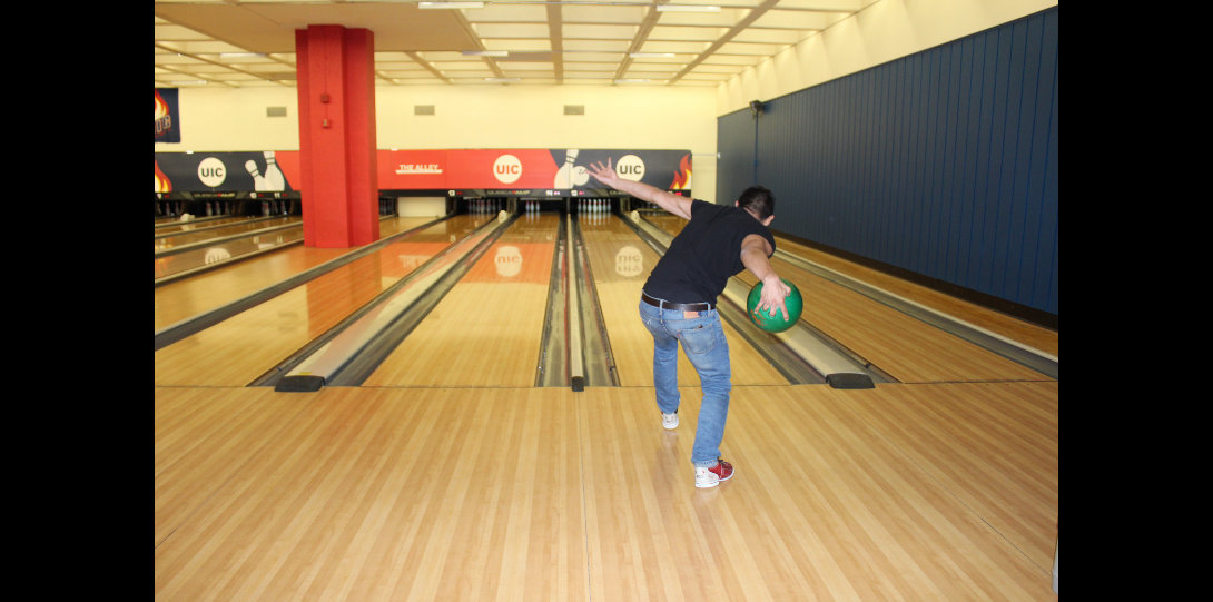 Hispanic male releasing her bowling ball down the bowling lane.