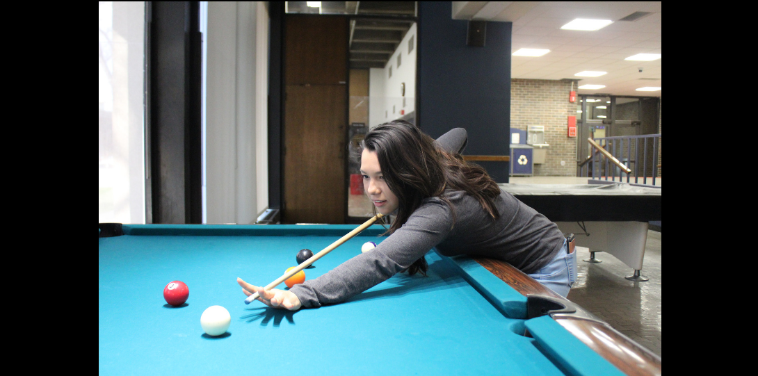 Hispanic female focusing on making a pool shot.