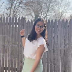 Woman wearing glasses and a dress with fence in the background